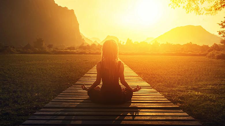 Woman meditating at sunrise